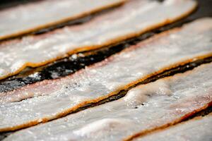 Pieces of bacon are fried in boiling oil with air bubbles. photo