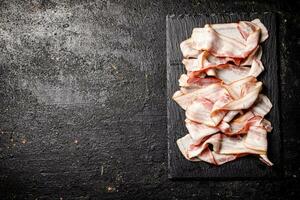 Pieces of fresh bacon on a stone board. photo