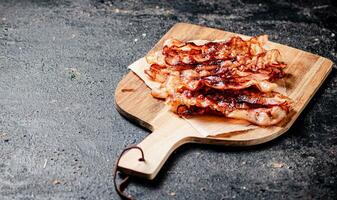 Fragrant pieces of fried bacon on a cutting board. photo