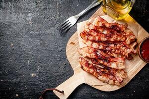 Pieces of fried bacon on a wooden cutting board. photo