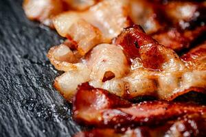 Strips of fried bacon on a black background. photo