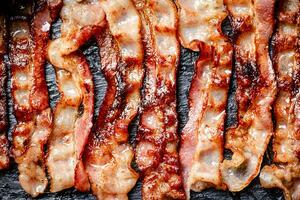 Strips of fried bacon on a black background. photo