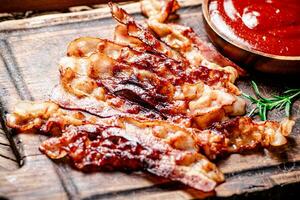 Pieces of fried bacon with tomato sauce. photo