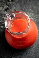 Jug with tomato juice on the table. photo