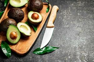 Fresh avocado with foliage on a cutting board. photo