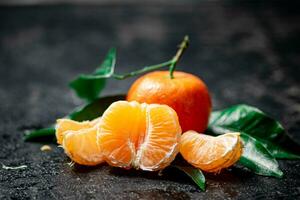 Ripe tangerines with foliage. On a black background. photo