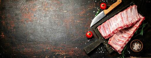 Raw ribs with spices and tomatoes on the table. photo