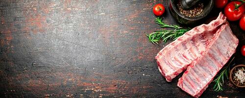 Raw ribs with spices and tomatoes on the table. photo