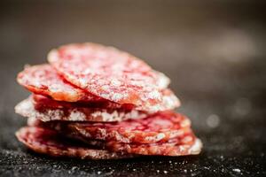 Sliced delicious salami sausage. On a black background. photo