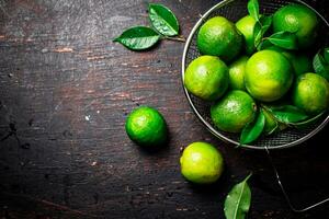 Fresh lime with leaves in a colander. photo
