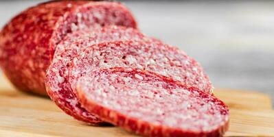 Cut into pieces of salami on a wooden cutting board. photo