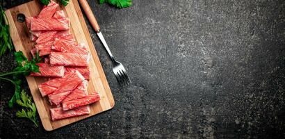 Crab meat on a cutting board with greens. photo