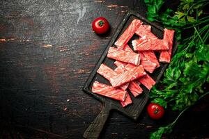 Crab meat on a cutting board with parsley and tomatoes. photo