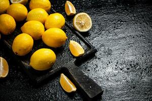 Pieces and whole lemons on a cutting board. photo