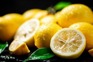 Juicy lemons with leaves on a stone board. photo