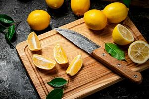 Sliced fresh lemons on a wooden cutting board with a knife. photo