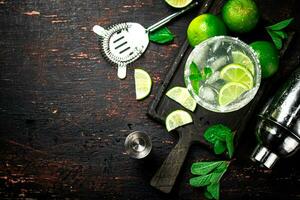 Margarita on a cutting board with pieces of lime and mint leaves. photo