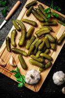 Pickles on a cutting board with garlic and parsley. photo