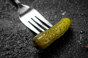 One pickled cucumber on a fork. photo
