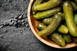 Wooden plate with pickles. On a black background. photo