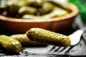 Wooden plate with pickles. On a black background. photo