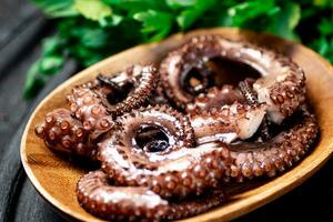 Pieces of octopus on a cutting board with parsley. photo