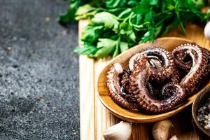 Fresh octopus on a plate on a cutting board with herbs and spices. photo