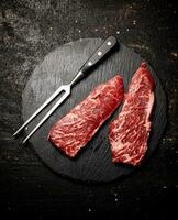 Raw steak on a stone board. On a black background. photo