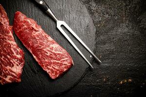 Raw steak on a stone board. On a black background. photo
