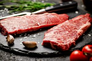 Raw steak on a stone board. On a black background. photo