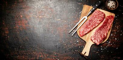 Raw steak on a wooden cutting board with spices. photo