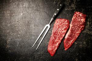 Raw steak with fork on the table. photo