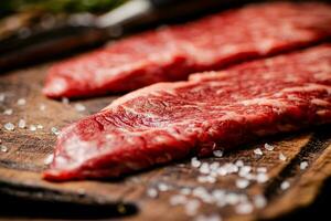 Raw steak with spices on a wooden cutting board. photo