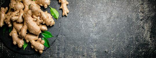 Fresh ginger with leaves on a stone board. photo