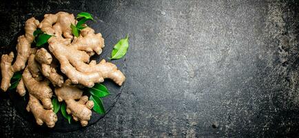 Fresh ginger with leaves on a stone board. photo