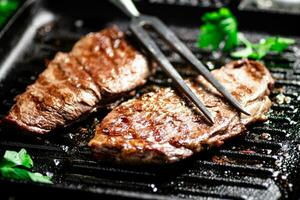 Grilled steak with parsley in a frying pan. photo