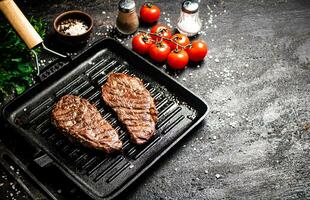 Grilled steak in a frying pan with tomatoes and spices. photo