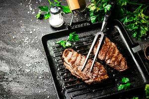 Grilled steak with parsley in a frying pan. photo