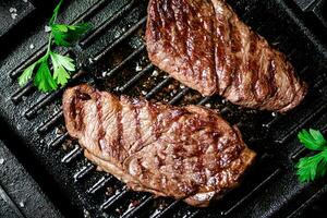 Grilled steak with parsley in a frying pan. photo