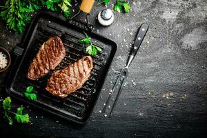 Grilled steak with parsley in a frying pan. photo