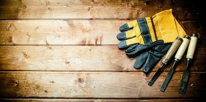 Chisel with construction gloves on the table. photo