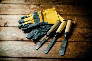 Chisel with construction gloves on the table. photo