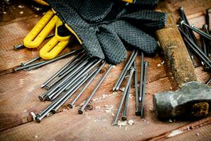 Hammer with nails and gloves on the table. photo