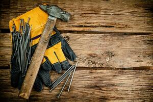 Hammer with nails and gloves on the table. photo