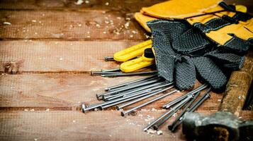 Hammer with nails and gloves on the table. photo