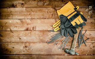 Hammer with nails and gloves on the table. photo