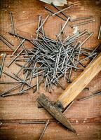 Hammer with a bunch of nails on the table. photo