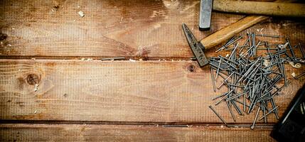 Hammer with a bunch of nails on the table. photo