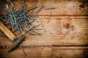 Hammer with a bunch of nails on the table. photo