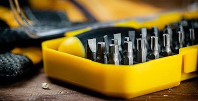 Working tools. Screwdriver bits. On a wooden background. photo